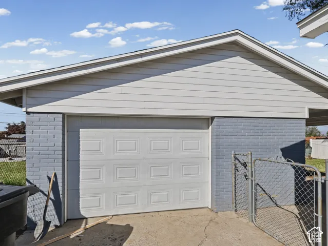 Attached garage featuring a panel-style garage door and brick-finish siding