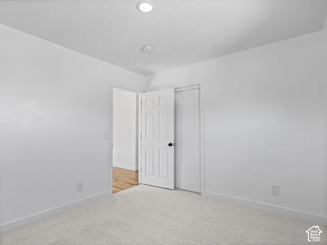Recessed ceiling lighting, white interior door with black hardware, and light-colored carpeting