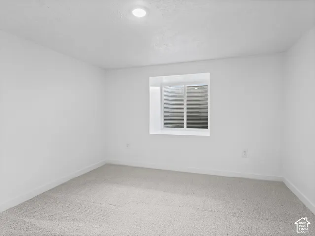 Recessed ceiling lighting with a window well, light-toned carpeting, and white wall finishes