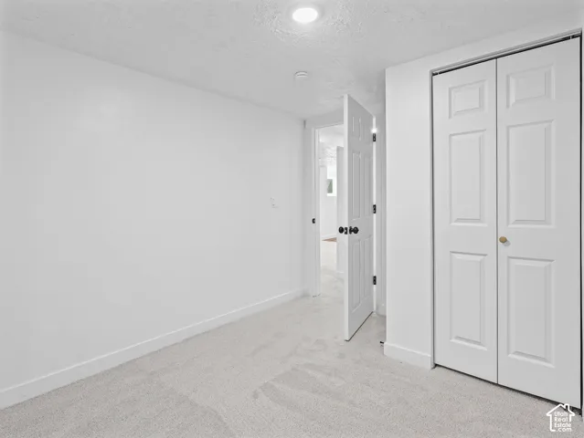 Recessed ceiling light, paneled bifold closet doors, light-toned carpeting, and white walls