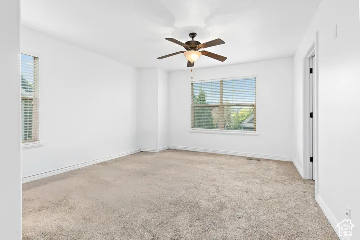 Neutral carpet flooring, white walls, and a ceiling fan with integrated lighting