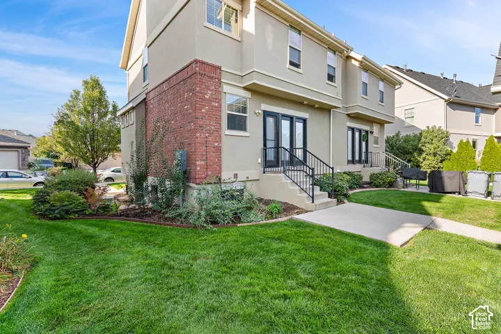 Stucco exterior with brick detailing, multiple windows, and dual sets of French doors