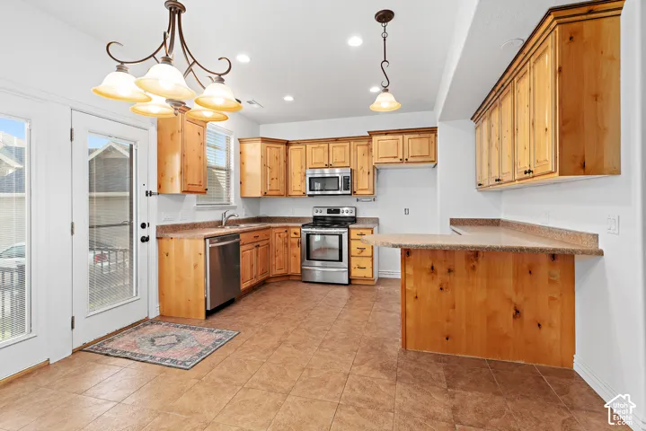 Kitchen featuring warm wood cabinetry, stainless steel appliances, durable tiled flooring, and a breakfast bar