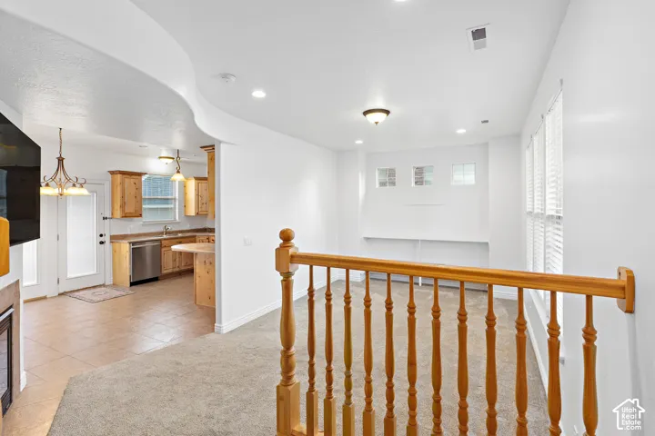 Kitchen with wood cabinetry, stainless steel dishwasher, and tiled flooring