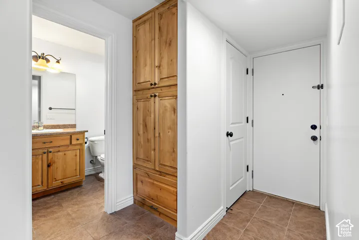Tile flooring throughout, full-height wood-finish cabinetry, and a white entry door