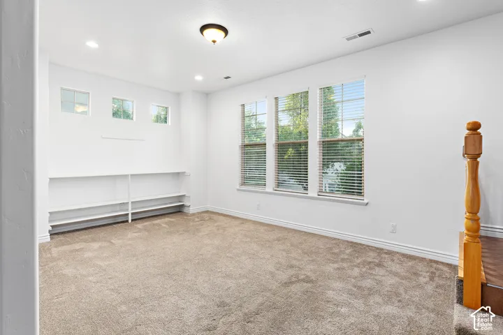 Spacious room featuring multiple windows with blinds, recessed lighting, a central ceiling light fixture, and built-in shelving