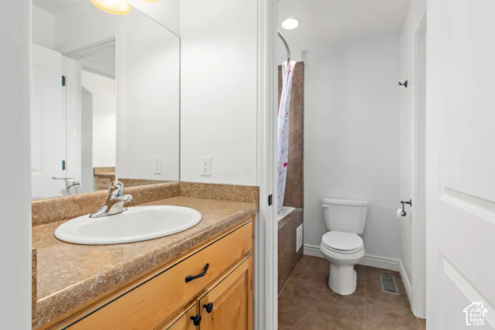 Bathroom featuring a light wood-finish vanity with dark hardware, a spacious countertop with an integrated sink, and an overhead light fixture