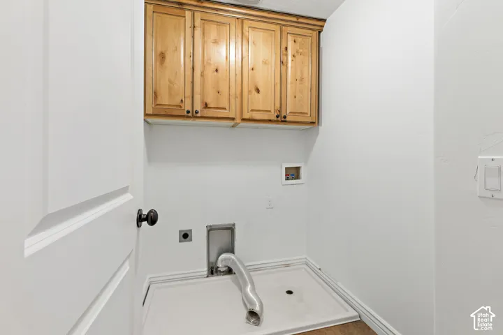 Upper wood-finish cabinetry, white paneled door with dark hardware, and light wood-finish flooring