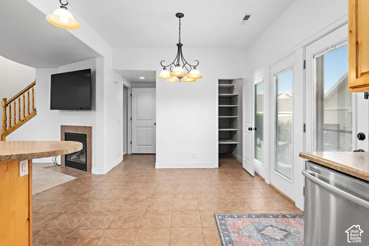 Tile flooring, built-in shelving, two glass-paneled doors, a fireplace with a stone surround, and wood cabinetry with a countertop