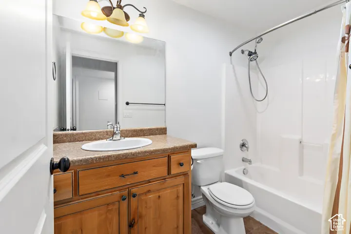 Bathroom featuring a vanity with wood-finish cabinetry, a white oval sink, and a speckled countertop