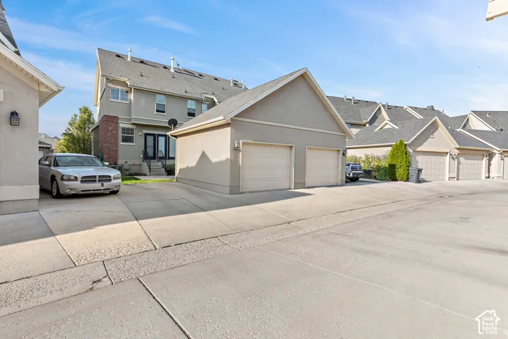 Detached two-car garage with overhead doors, concrete driveway, and exterior wall lanterns