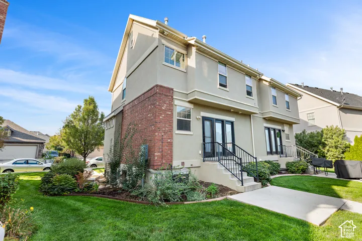 Stucco exterior featuring red brick accents, multiple windows, and two sets of double glass doors