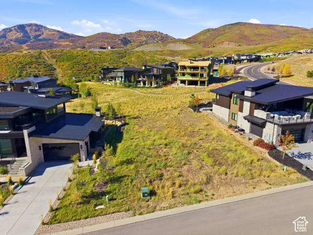 Expansive lot with natural landscaping, surrounded by modern residences with mountain backdrops