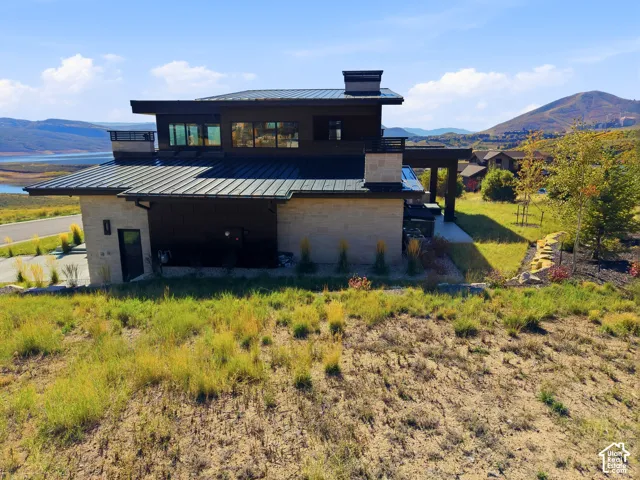 Contemporary architecture with a flat roofline, stone and dark siding exterior, multiple large windows, and a paved driveway