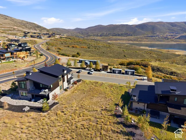 Modern architecture with a dark metal roof, stone and wood-panel siding, and a multi-level deck