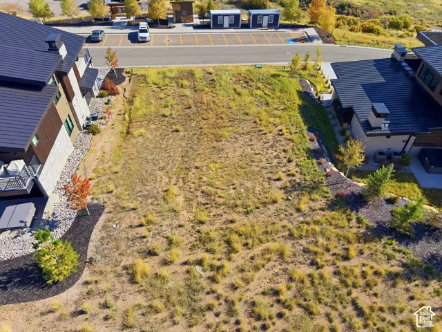 Expansive undeveloped lot with surrounding residential structures and paved road access