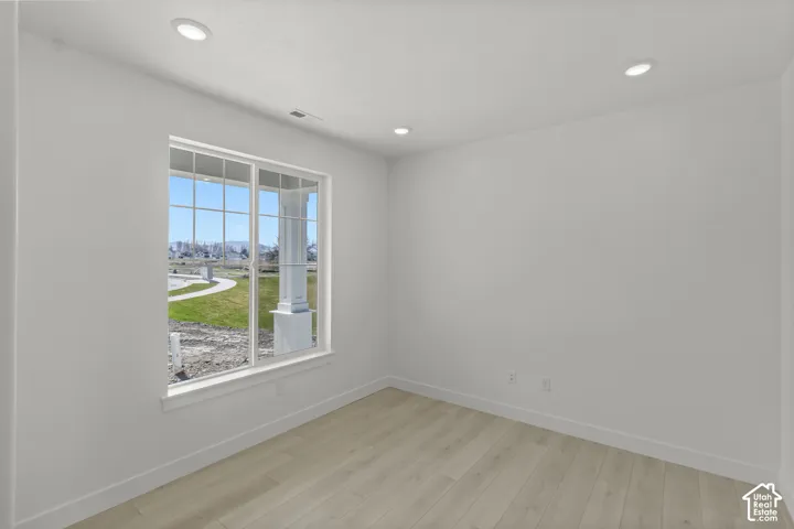 Recessed ceiling lighting, wood-finish flooring, white trim, and a large multi-pane window
