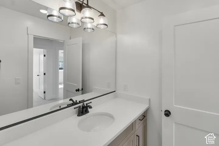 Vanity with a single undermount sink, a dark bronze faucet, and light wood-finish cabinetry