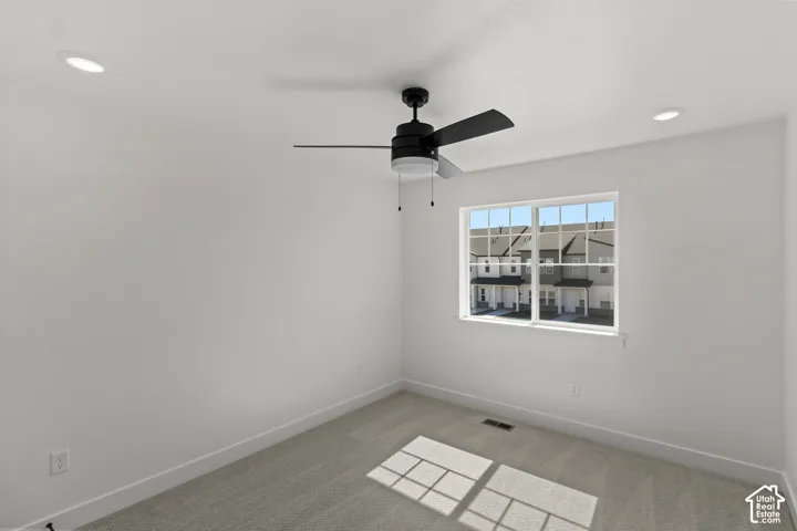 Bright room featuring a window with grid inserts, recessed lighting, a ceiling fan with light, and light-toned carpeting