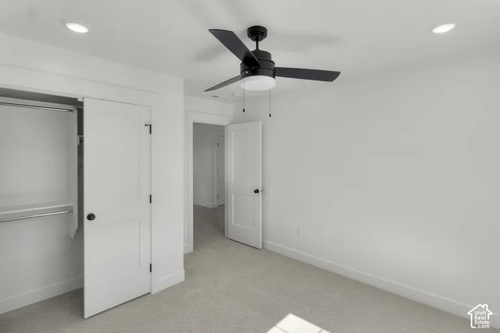 Recessed lighting, black ceiling fan with light, white flat-panel doors, black hardware, and gray carpeting