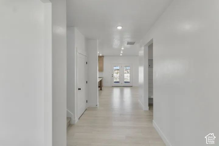 Light wood-finish flooring, recessed lighting, and white walls throughout