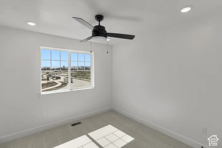 Recessed lighting, ceiling fan, large window with grid pattern, neutral carpet flooring, and white painted walls