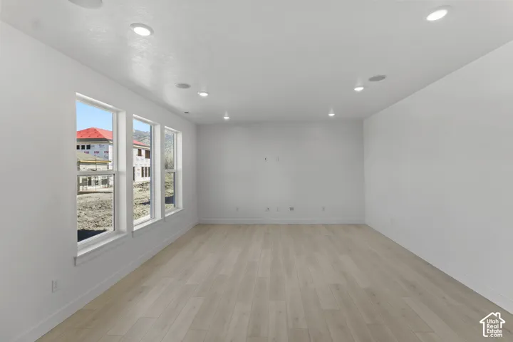 Recessed lighting, light wood-finish flooring, multiple windows, white wall finishes, and in-ceiling speakers