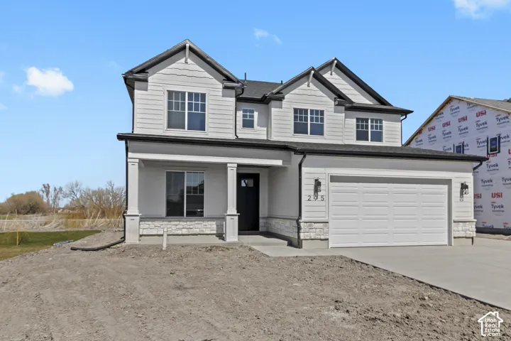 Two-story residence featuring light-colored siding, a two-car garage, and stone accent detailing