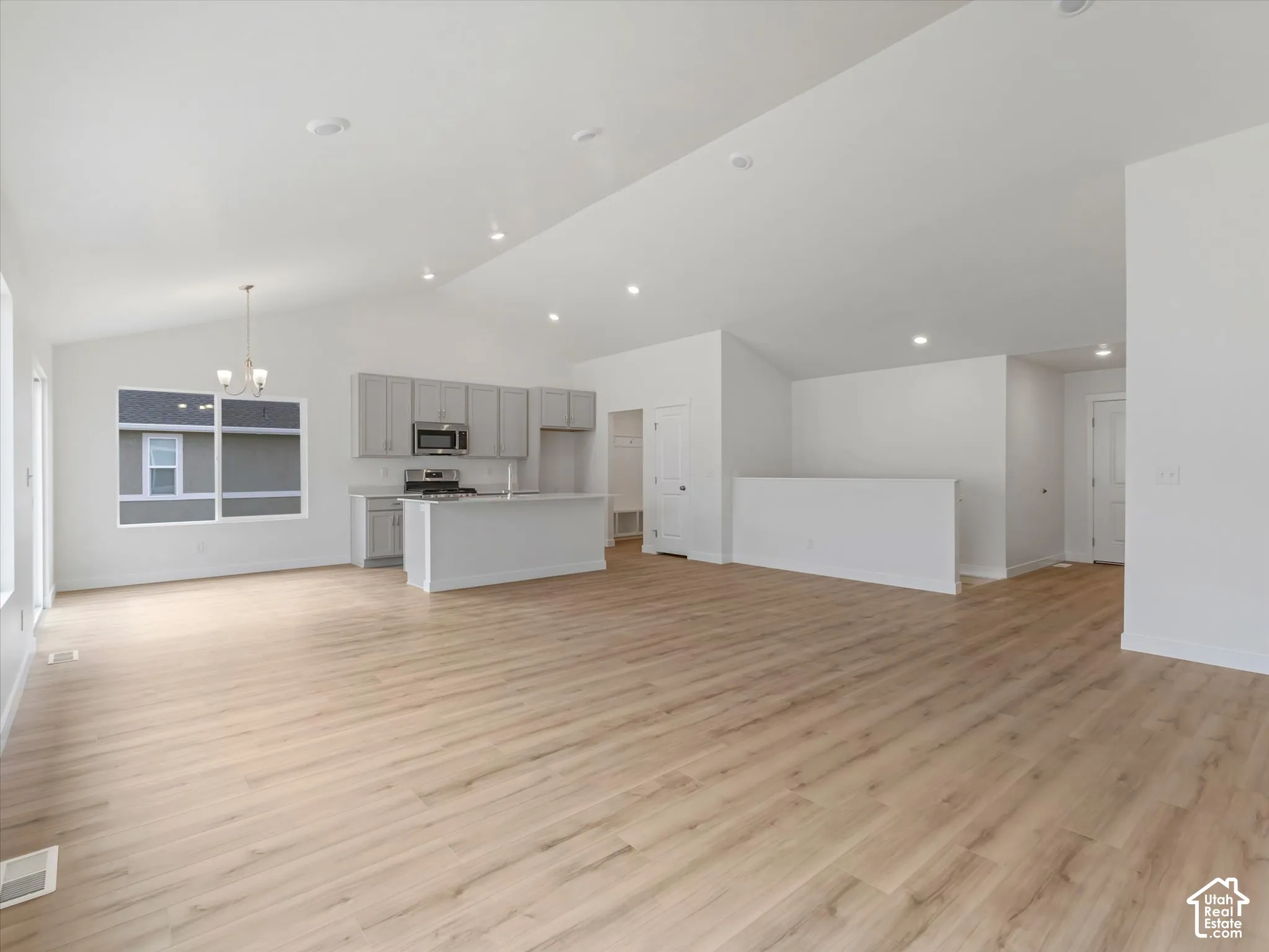 Open-concept living space featuring wood-finish flooring, vaulted ceilings, and recessed lighting