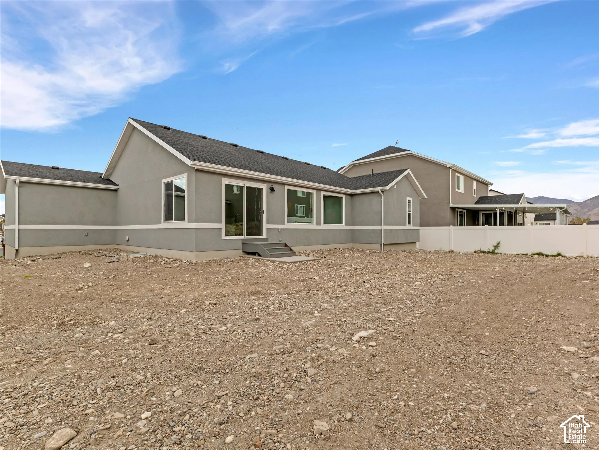 Gray stucco exterior with white trim, multiple windows, and a sliding glass door