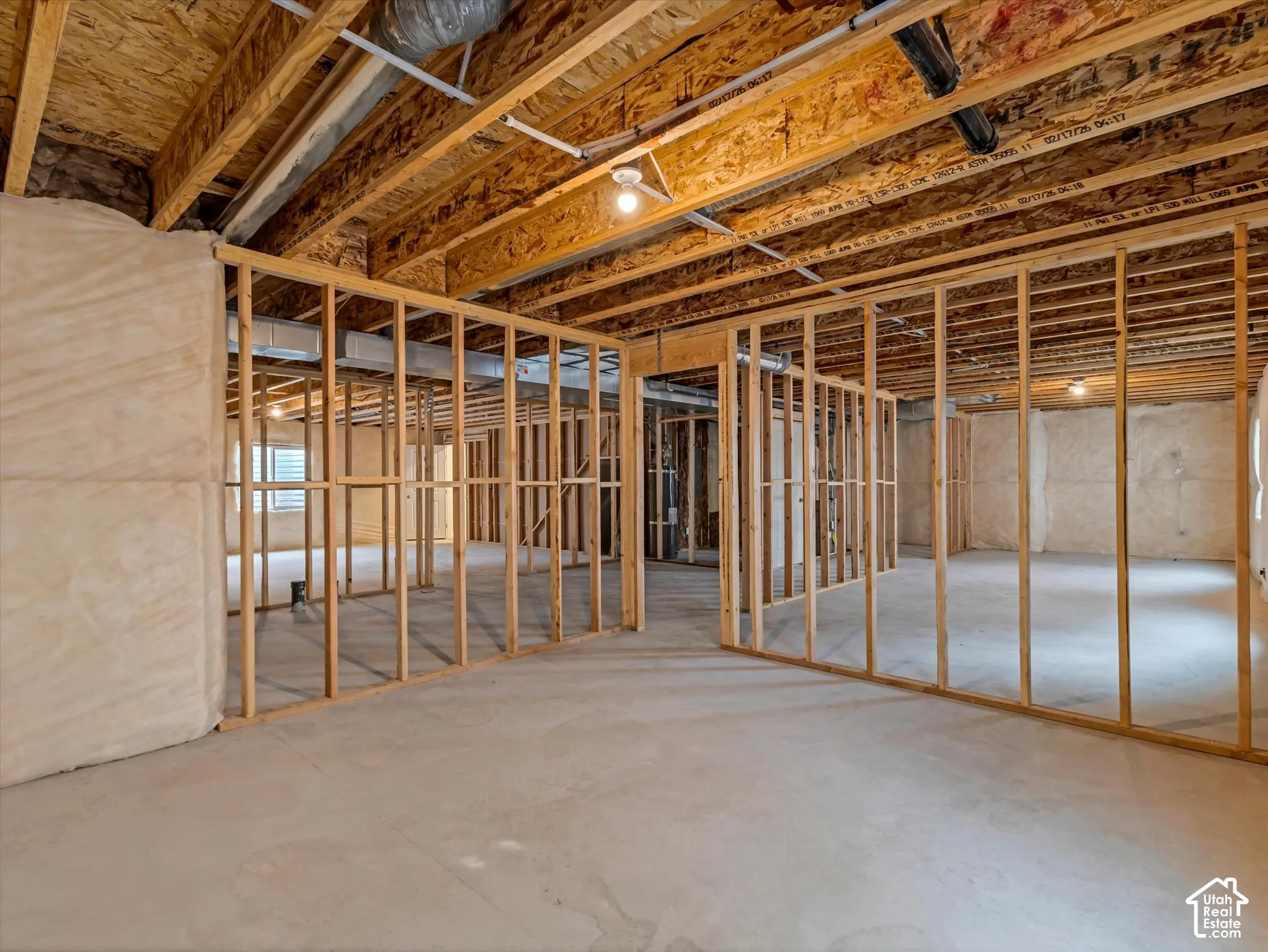 Unfinished basement with concrete flooring, exposed wood framing, and exposed ductwork
