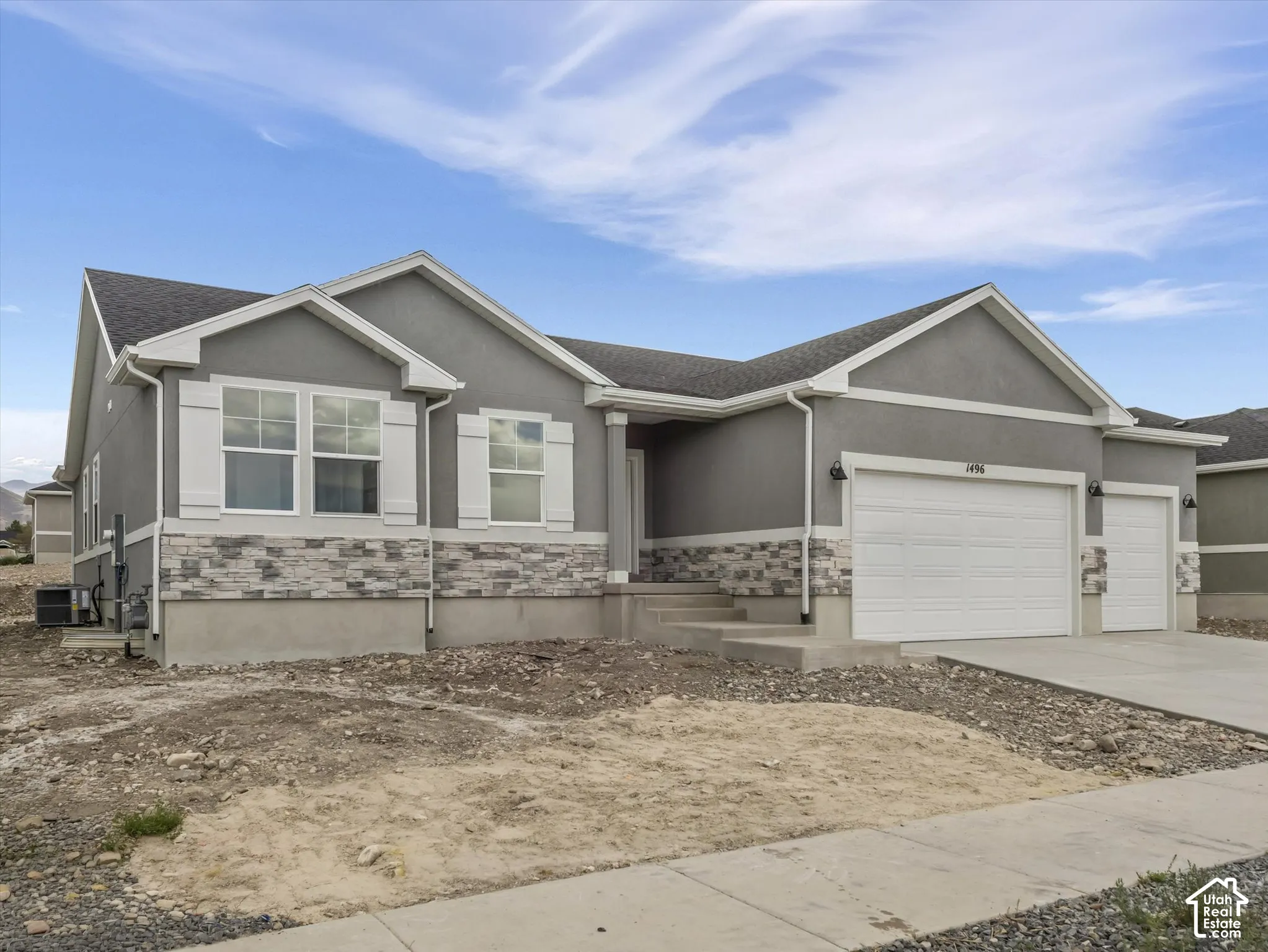 Gray stucco exterior with a stone veneer accent, white window shutters, and an attached two-car garage