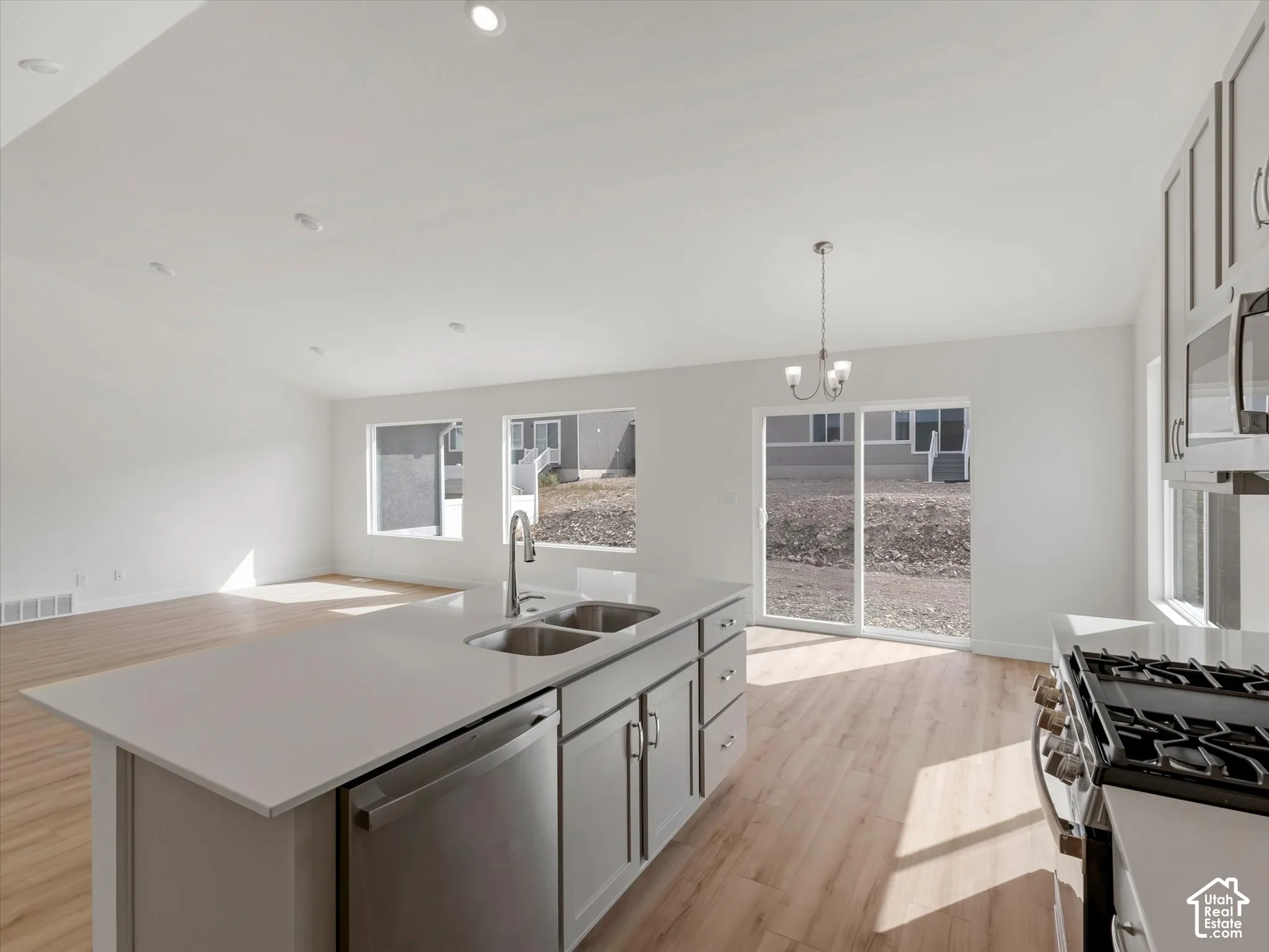 Spacious kitchen island with a double basin sink, stainless steel dishwasher, and quartz countertop