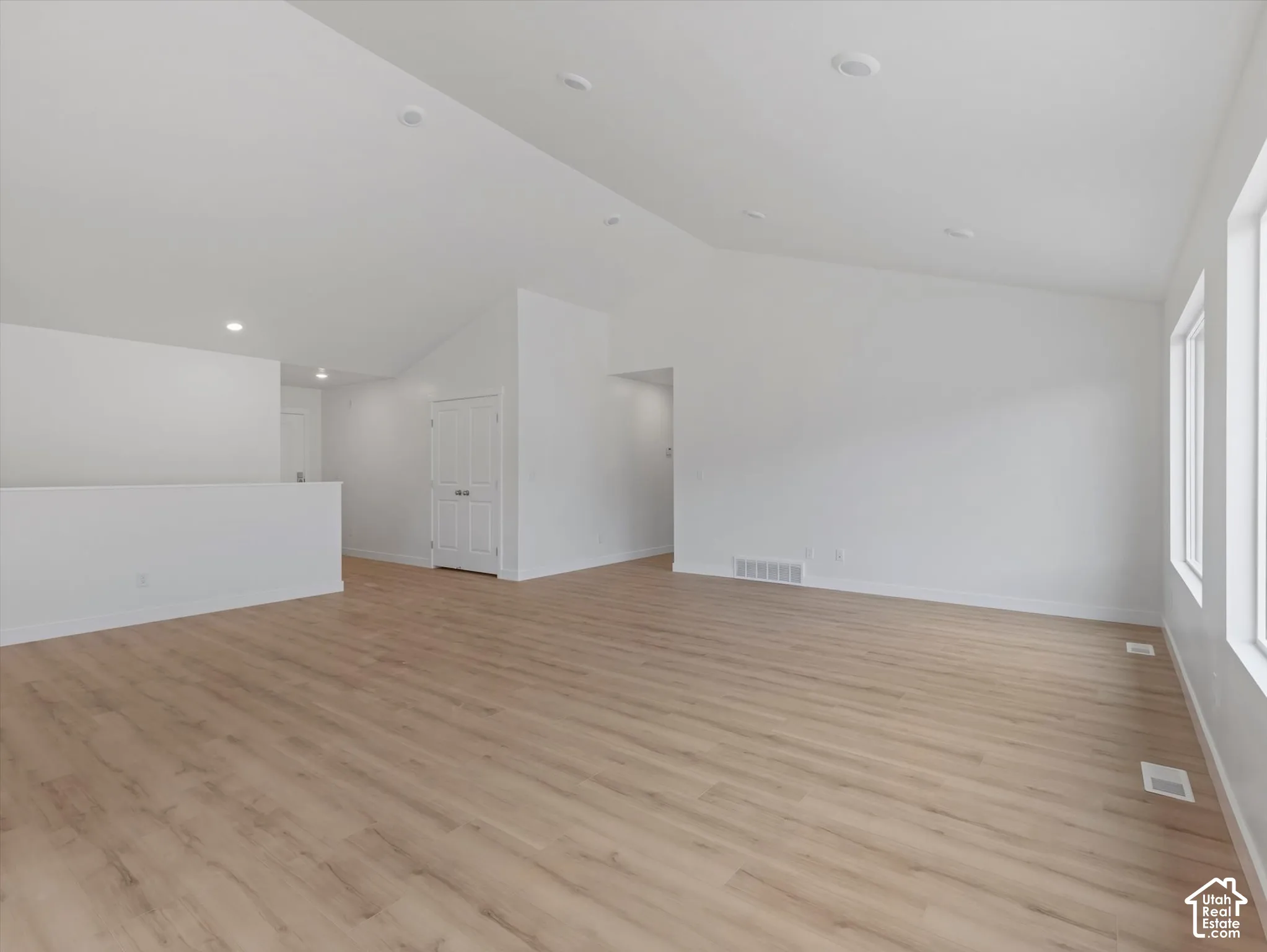 Vaulted ceilings, recessed lighting, wood-finish flooring, white walls, and bright windows