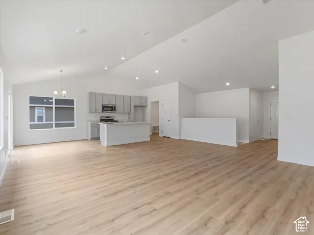 Open-concept living space featuring wood-finish flooring, vaulted ceilings, and recessed lighting