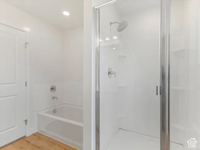 White shower enclosure with glass door, chrome fixtures, and built-in shelving