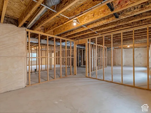 Unfinished basement with concrete flooring, exposed wood framing, and exposed ductwork