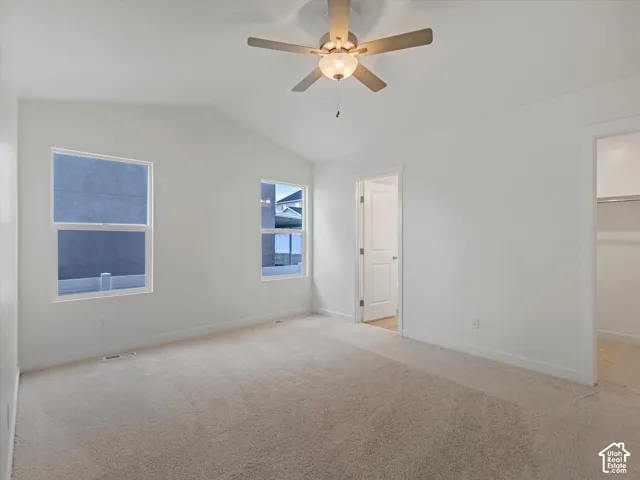 Vaulted ceiling with a ceiling fan, two windows, wall-to-wall carpeting, and white trim throughout