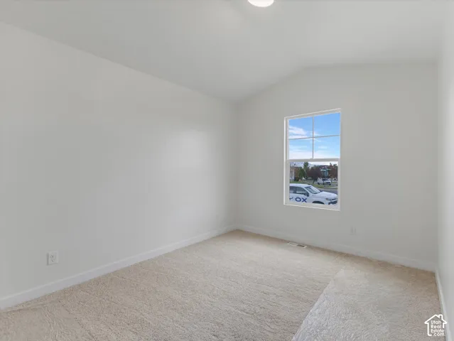 Neutral-toned wall-to-wall carpeting, white painted walls, and a single window with a white frame