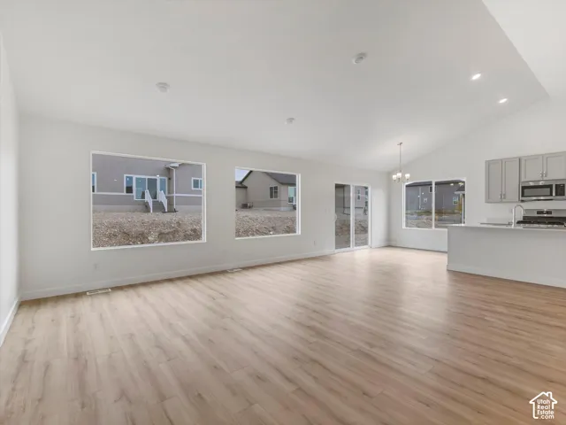 Vaulted ceiling with recessed lighting, wood-finish flooring, sliding glass door, kitchen island with countertop, and modern cabinetry