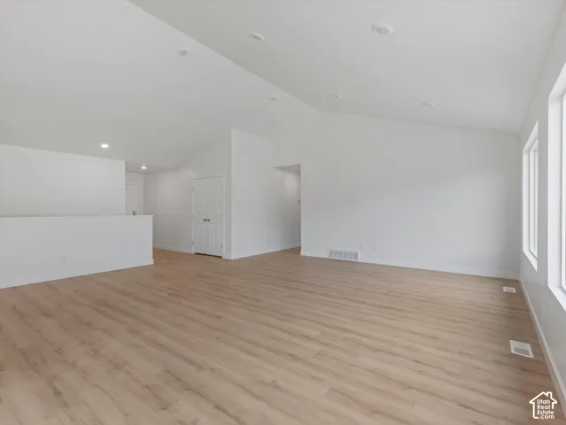 Vaulted ceilings, recessed lighting, wood-finish flooring, white walls, and bright windows