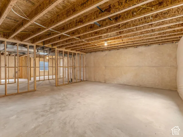 Unfinished basement with concrete flooring, exposed wood framing, ceiling joists, and insulated walls
