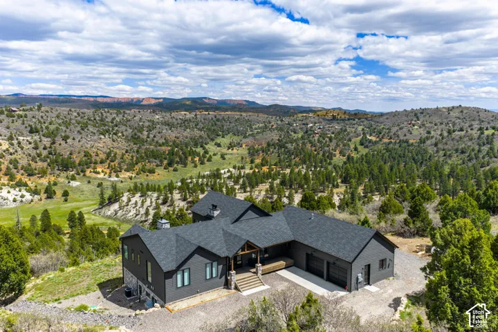 Contemporary exterior with dark siding, stone accents, multiple gables, an attached three-car garage, and a covered entry