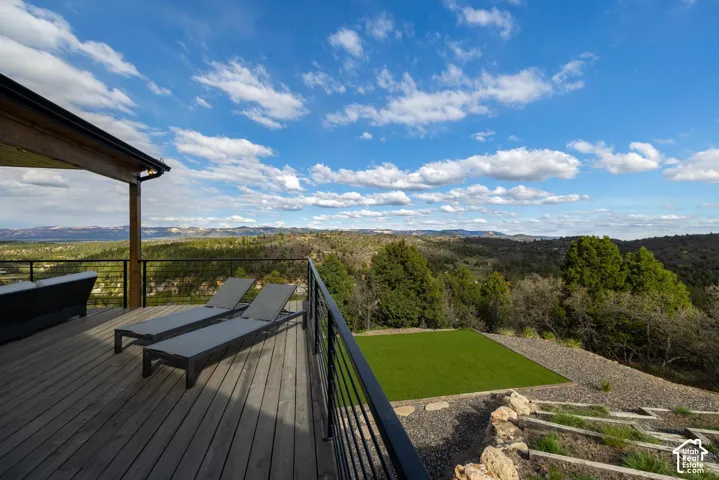 Expansive wood deck with cable railing overlooking a vast natural landscape