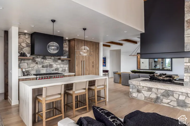 Open concept living area featuring a stone-clad fireplace and light wood-finish flooring