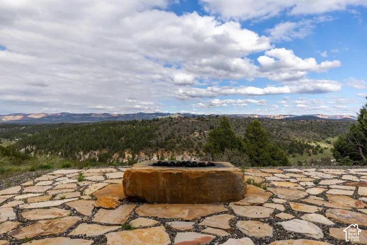 Stone patio with a built-in fire pit, featuring a natural stone surround and a vast natural landscape backdrop