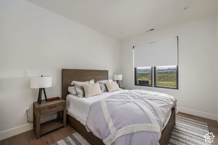 Recessed lighting, wood-finish flooring, and a large window with roller shades