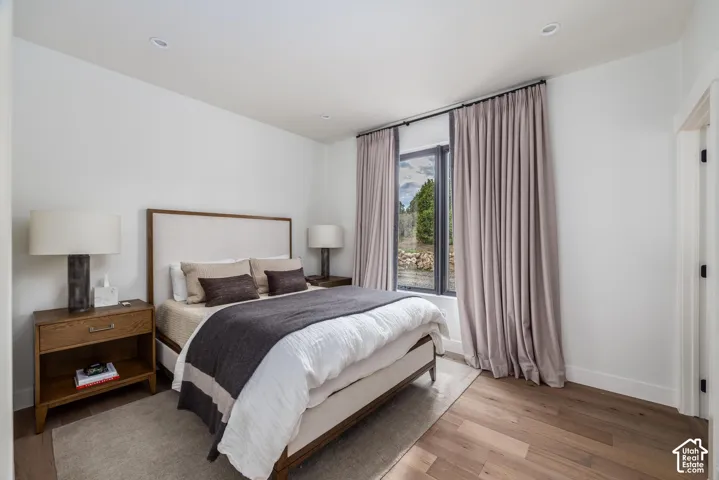 Recessed lighting, wood-finish flooring, and a large window with privacy treatments