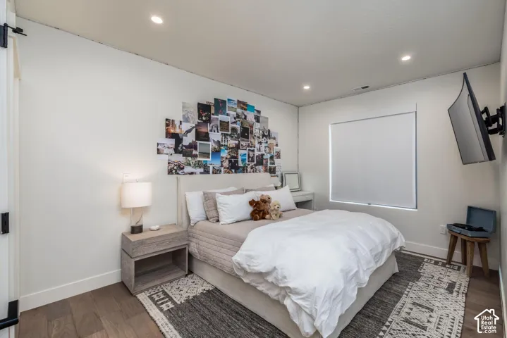 Recessed lighting, light wood-finish flooring, white walls, and a window with a roller shade