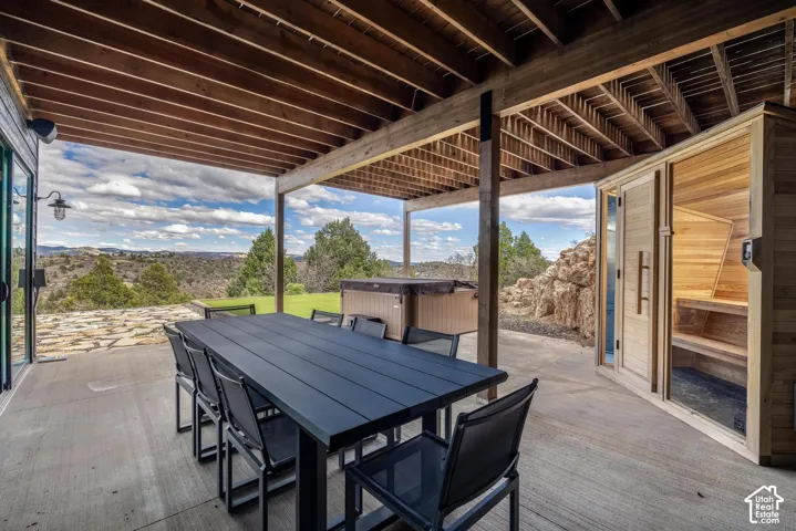 Covered outdoor patio with exposed timber ceiling, concrete slab flooring, and a built-in outdoor sauna
